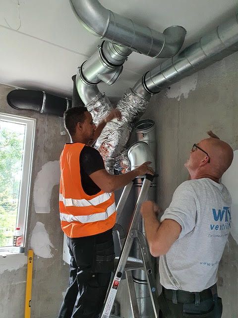Twee monteurs van WTW Ventilatie werken aan ventilatiekanalen