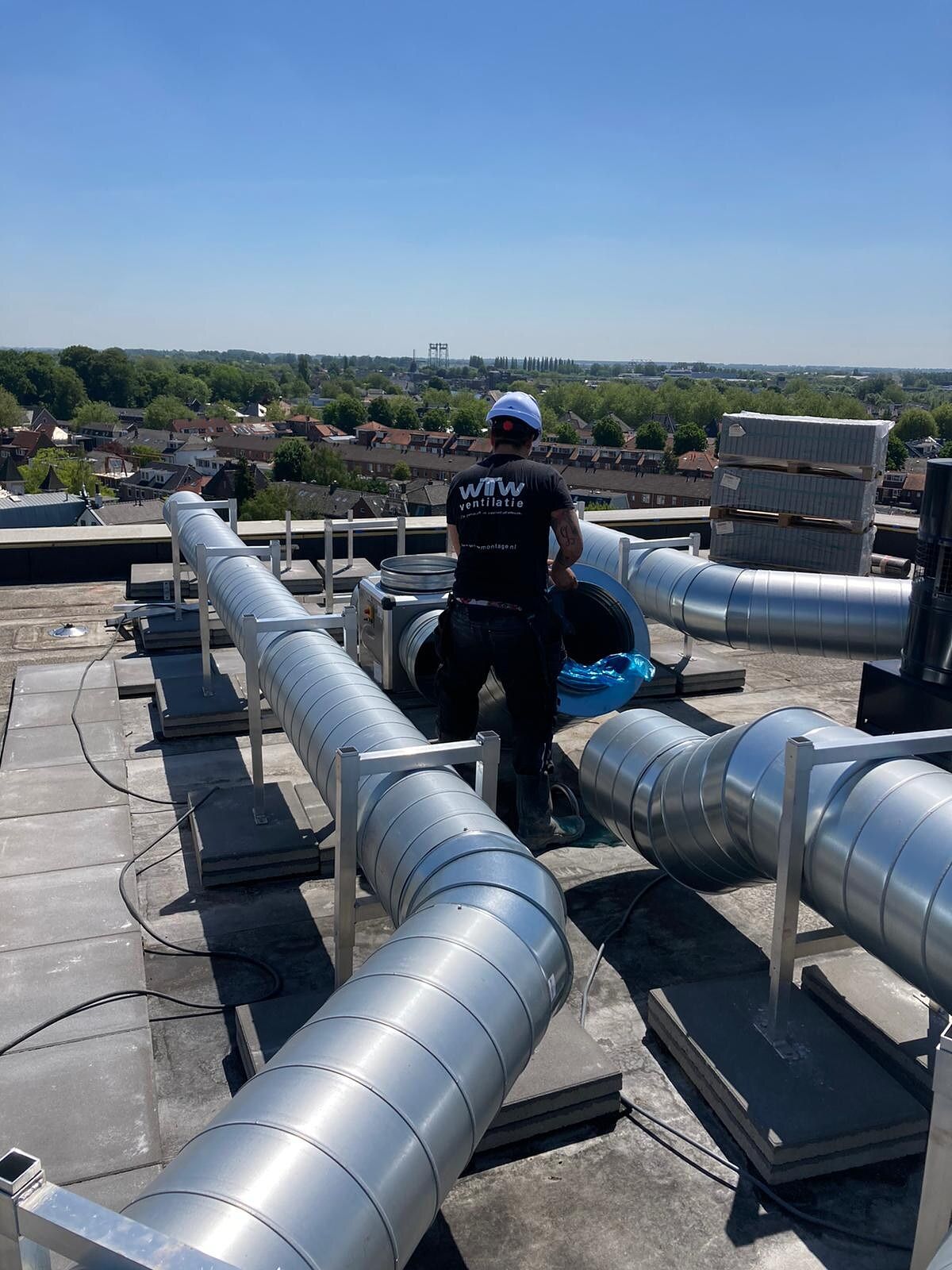 Monteur inspecteert ventilatiekanalen op een dak