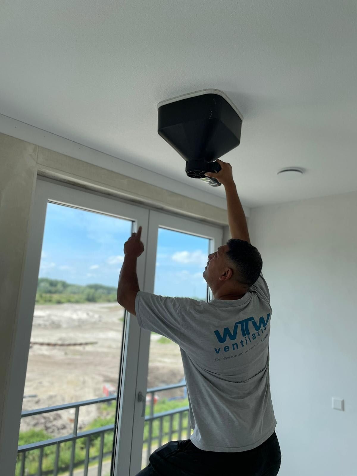 Monteur van WTW Ventilatie plaatst een ventiel in een nieuwbouwwoning